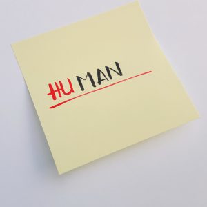 Sticky note with word human with letters HU in red and MAN in black as symbol of sexist language